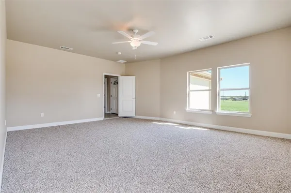 an empty room with windows and chandelier fan