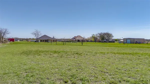 a view of a field with lawn chairs and trees
