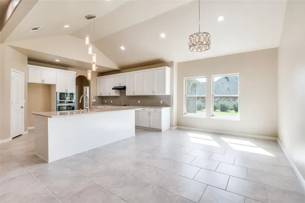 a large kitchen with kitchen island granite countertop a stove a sink a refrigerator and a counter top space
