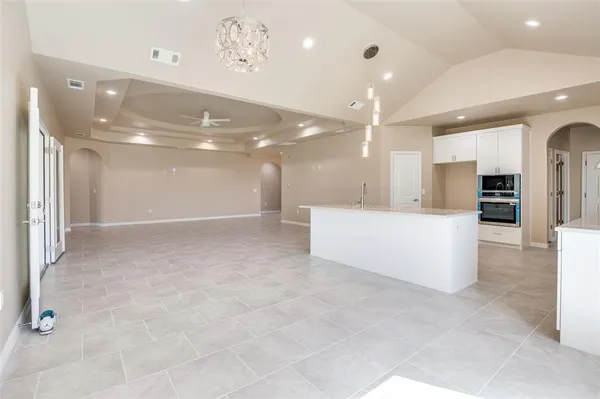 a large white kitchen with kitchen island a sink stainless steel appliances and cabinets