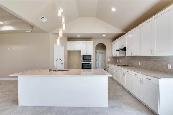 a large kitchen with stainless steel appliances kitchen island a large counter top and a stove top oven