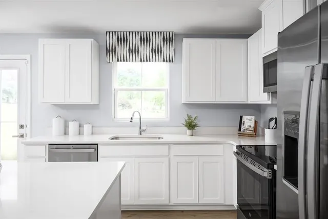 a kitchen with stainless steel appliances granite countertop a sink a stove a refrigerator and cabinets