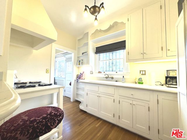 a kitchen with a stove a refrigerator and a dining table with wooden floor