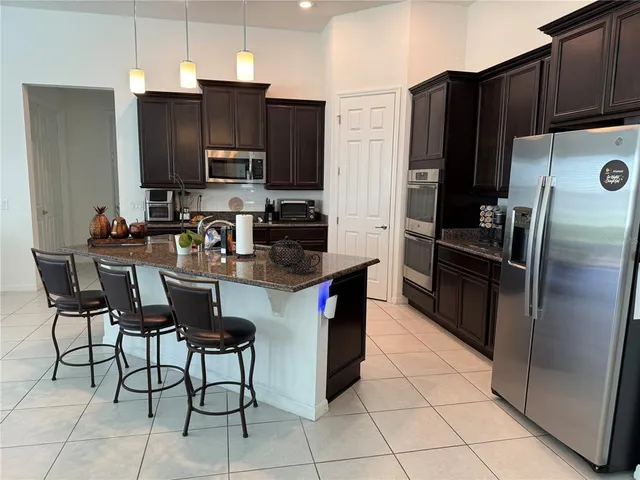 a kitchen with granite countertop a refrigerator and a stove top oven