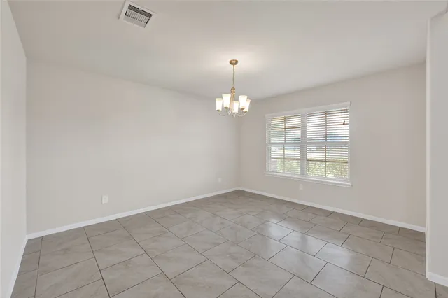 an empty room with chandelier fan and windows