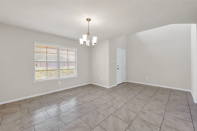 an empty room with chandelier fan and windows
