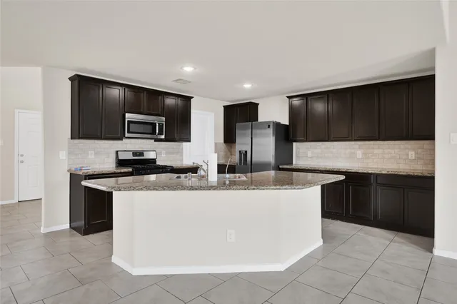 a large kitchen with stainless steel appliances a stove a sink a microwave and cabinets