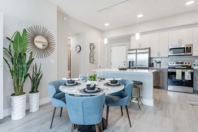 a dining room with furniture a potted plant and kitchen view