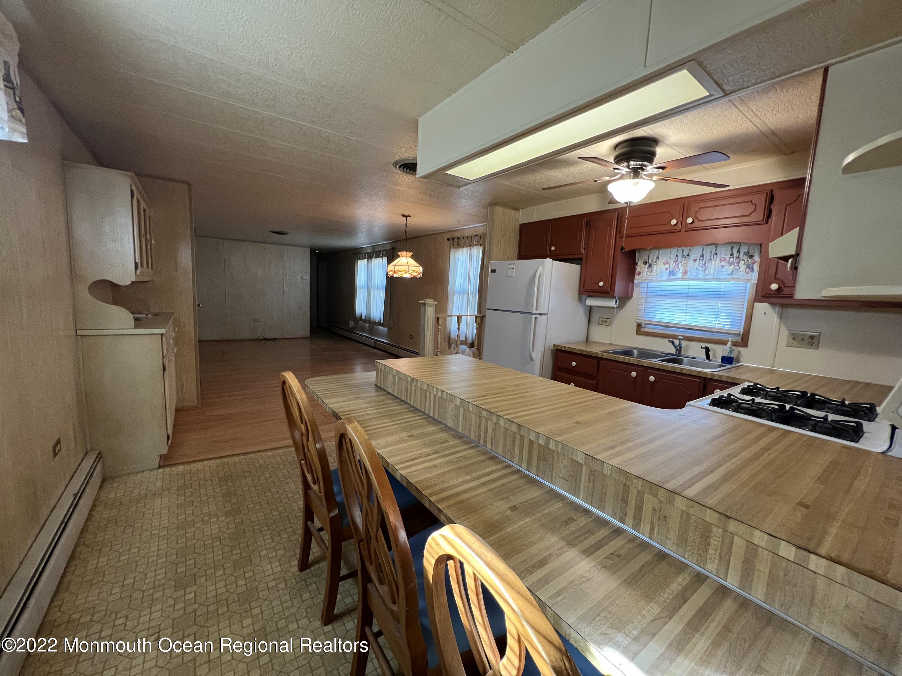 705 Aviary Way Toms River, NJ 08755 - Photo 8 of 14 a kitchen with stainless steel appliances granite countertop a table chairs in it and wooden floors