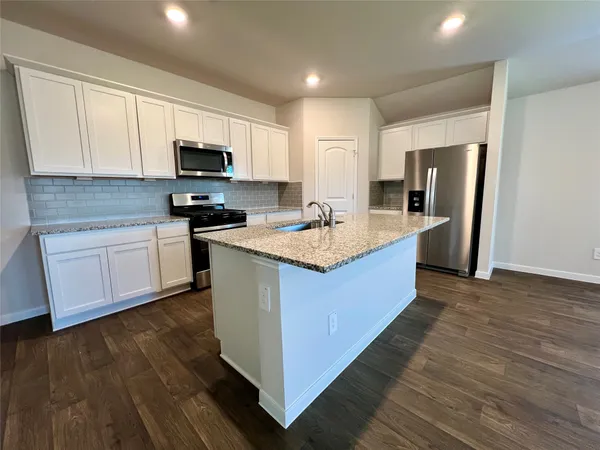 a large kitchen with stainless steel appliances granite countertop a stove a sink dishwasher a refrigerator and a microwave oven with wooden floor