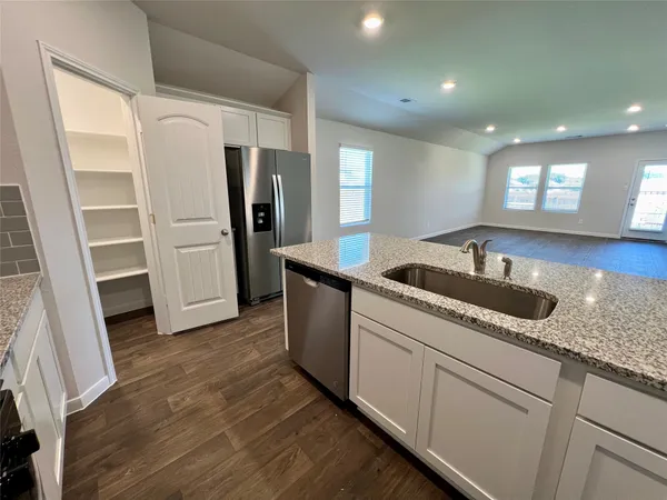 a kitchen with granite countertop a refrigerator and a sink