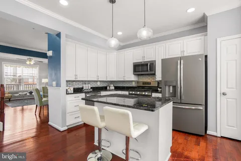 a kitchen with a refrigerator a microwave oven a stove and white cabinets with wooden floor