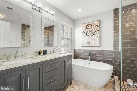 a bathroom with a double vanity sink mirror and bathtub
