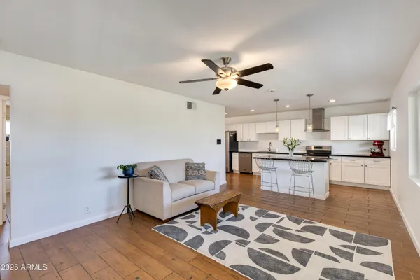a living room with a couch and kitchen view with wooden floor