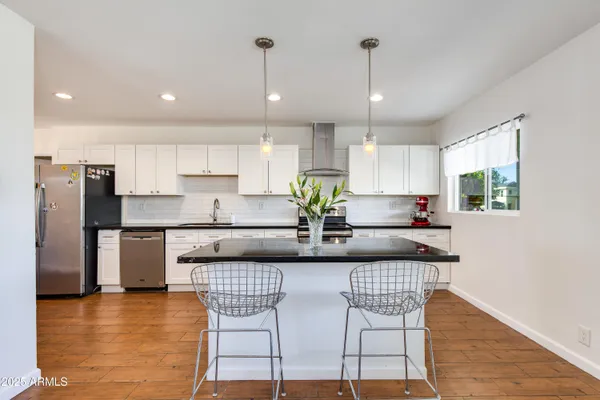a kitchen with stainless steel appliances granite countertop a stove top oven a refrigerator a sink and a dining table with wooden floor