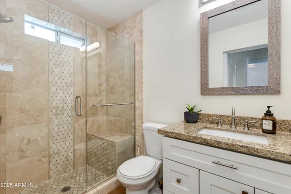 a bathroom with a granite countertop sink a toilet and shower