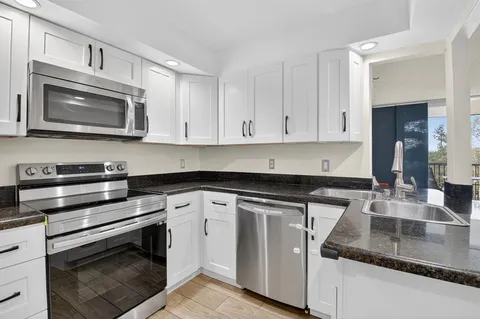 a kitchen with granite countertop white cabinets and stainless steel appliances