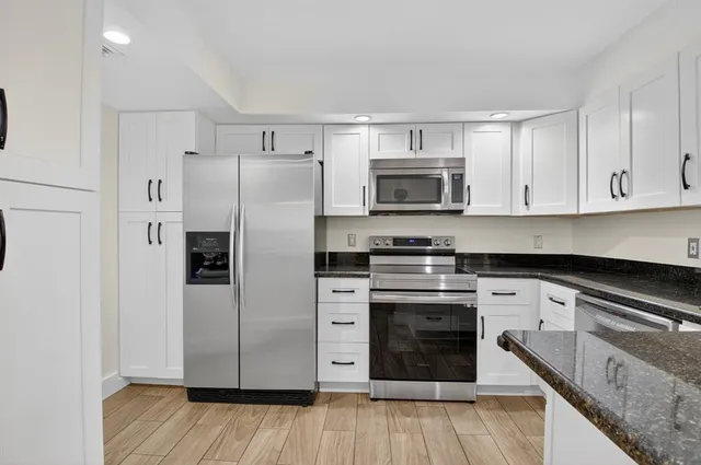 a kitchen with stainless steel appliances white cabinets a sink a stove a refrigerator and microwave