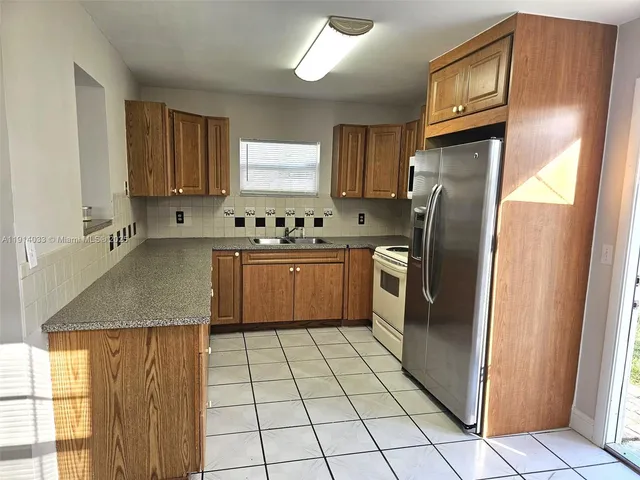 a kitchen with stainless steel appliances granite countertop a refrigerator a sink a stove a washer dryer and cabinets