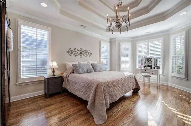 a spacious bedroom with a large bed a chandelier and windows