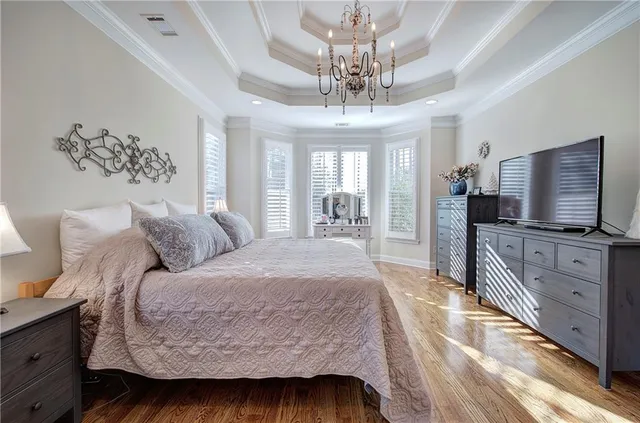 a spacious bedroom with a large bed a flat tv screen and a dresser