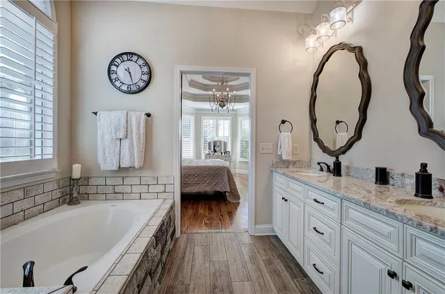 a spacious bathroom with a tub a double vanity sink and a mirror