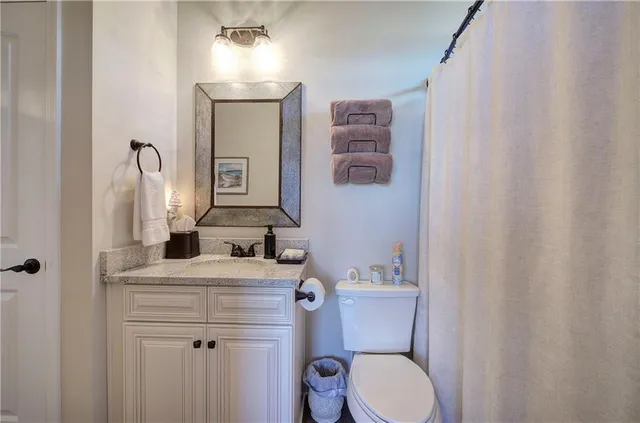 a bathroom with a granite countertop toilet sink and mirror