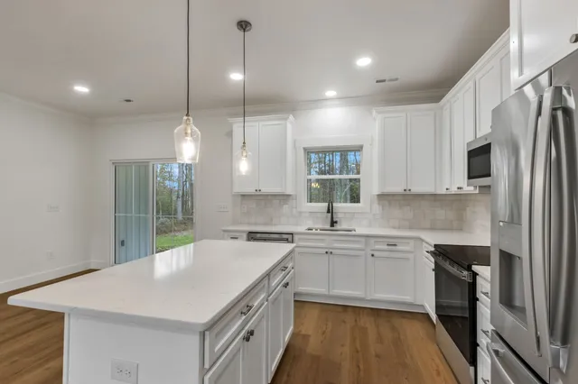 a kitchen with a sink a stove a refrigerator and white cabinets