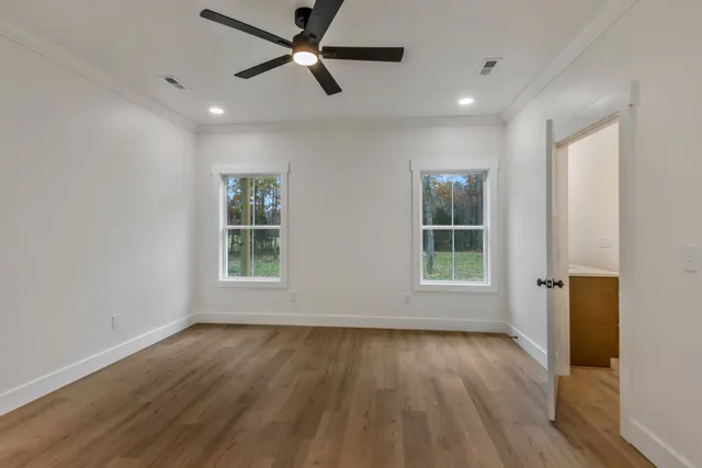a view of empty room with wooden floor and fan
