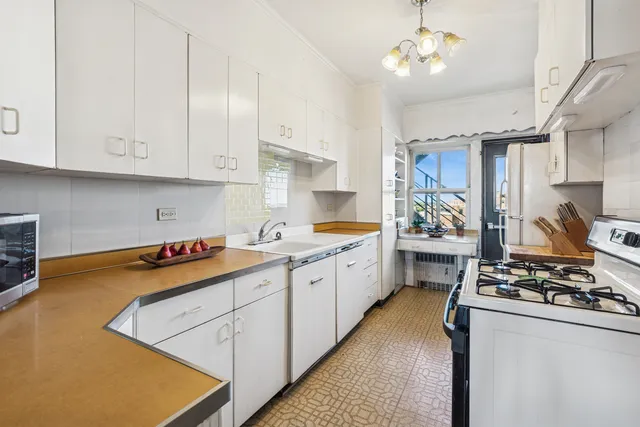 a kitchen with stainless steel appliances granite countertop a stove a sink dishwasher and white cabinets with wooden floor