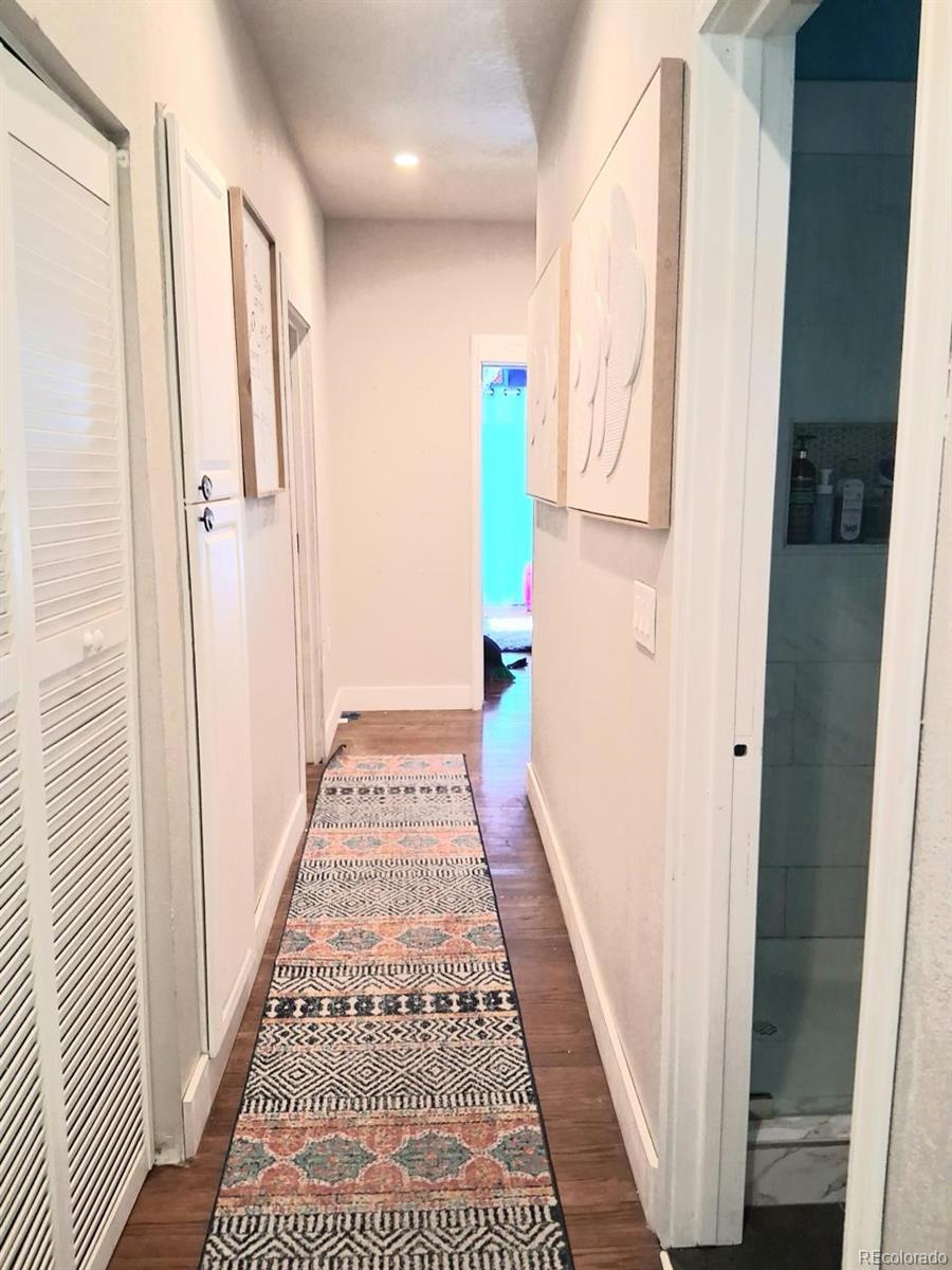 451 Acoma Street Denver, CO 80204 - Photo 7 of 19 a view of a hallway with wooden floor and a bathroom