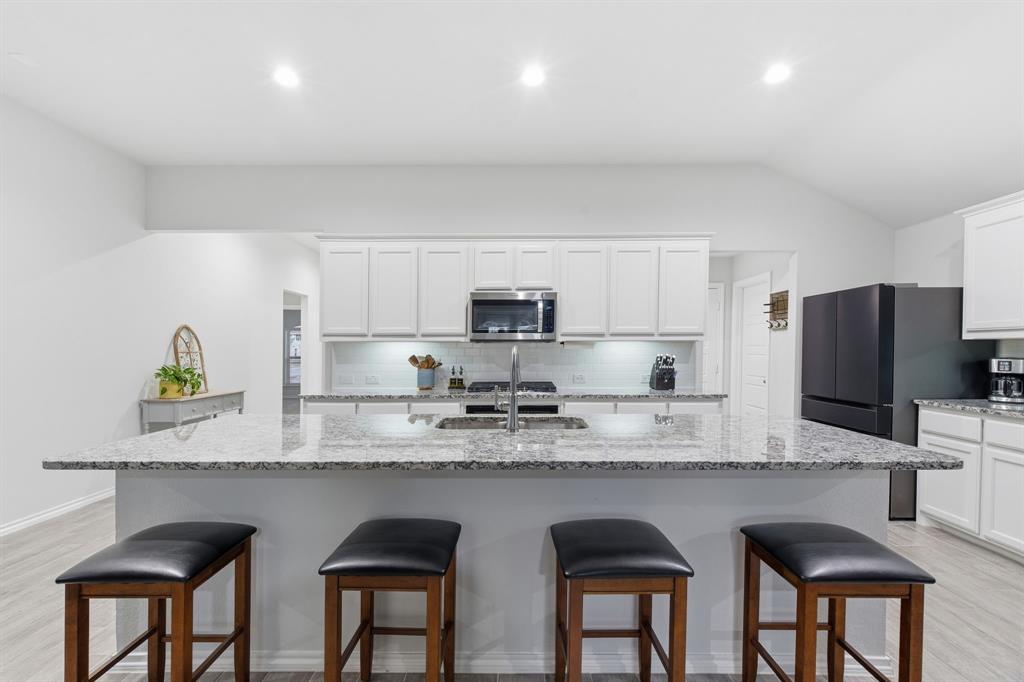 437 Falcon Way Azle, TX 76020 - Photo 11 of 40 a kitchen with stainless steel appliances granite countertop a sink a stove a refrigerator cabinets and chairs