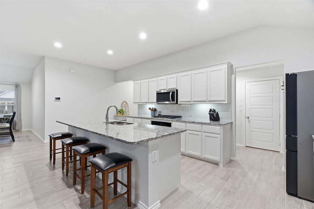 437 Falcon Way Azle, TX 76020 - Photo 12 of 40 a kitchen with white cabinets and stainless steel appliances