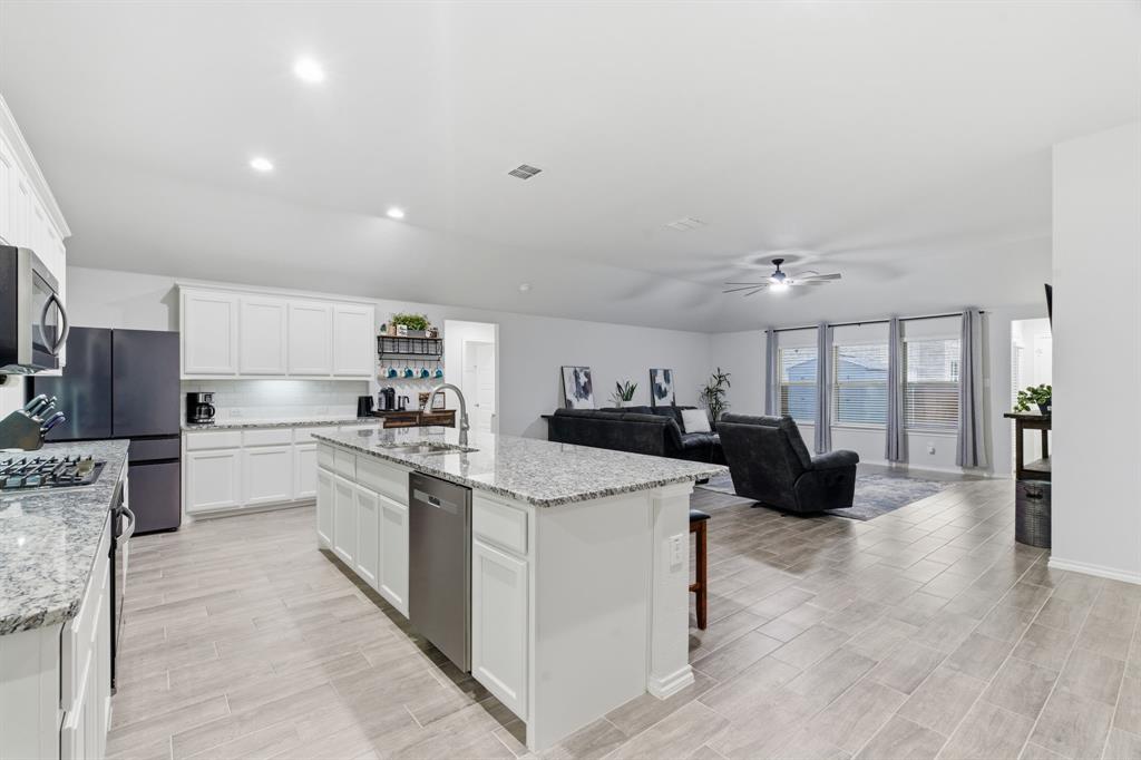 437 Falcon Way Azle, TX 76020 - Photo 10 of 40 a large white kitchen with a stove a sink dishwasher and a fireplace with wooden floor
