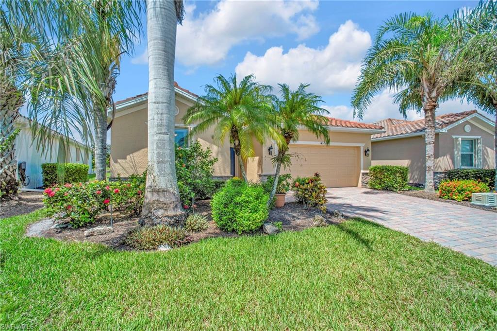 Street view an attached garage, stucco siding, paver driveway, a tile roof, and mature palms