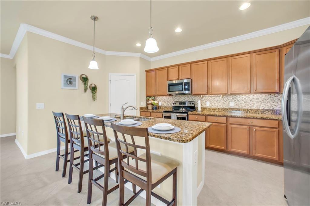 14513 Lanier Court Naples, FL 34114 - Photo 20 of 42 Kitchen with stone countertops, tasteful backsplash, crown molding, a breakfast bar area, and walk in pantry