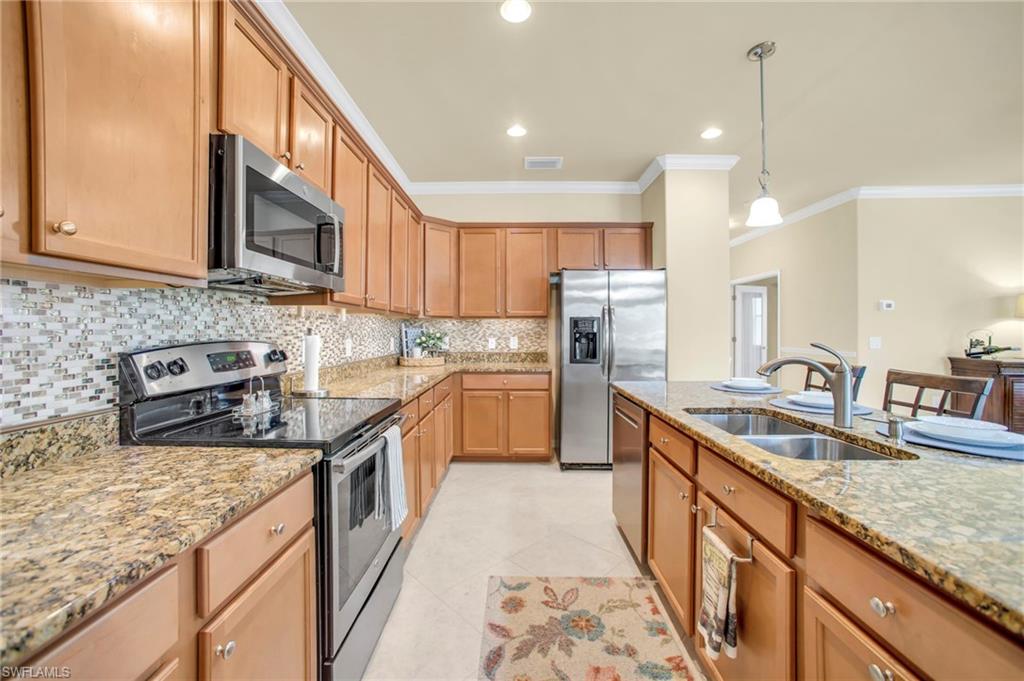 14513 Lanier Court Naples, FL 34114 - Photo 22 of 42 Kitchen with stainless steel appliances, pendant lighting, backsplash, stone counters, and crown molding