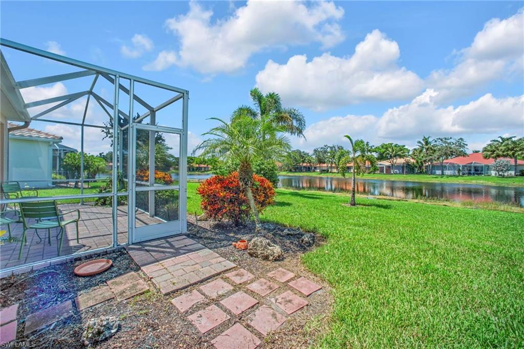 14513 Lanier Court Naples, FL 34114 - Photo 30 of 42 View of green lawn with a patio area, a lanai, a water view, and a sunroom