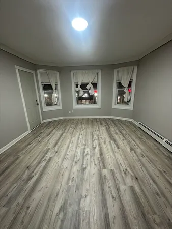 an empty room with wooden floor and windows