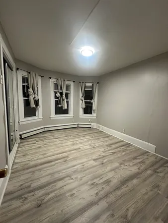 a view of an empty room with a window and wooden floor