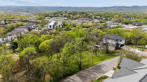 an aerial view of residential houses with outdoor space and trees