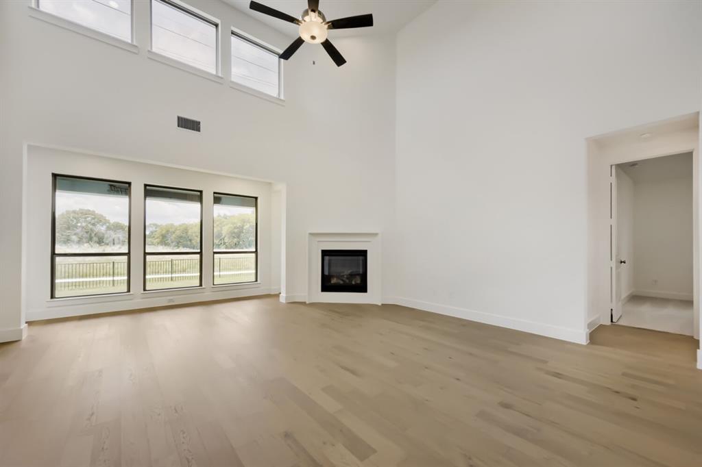 11465 Wulstone Road Fort Worth, TX 76052 - Photo 6 of 27 Vaulted living space featuring wood-finish flooring, a corner fireplace, and a ceiling fan