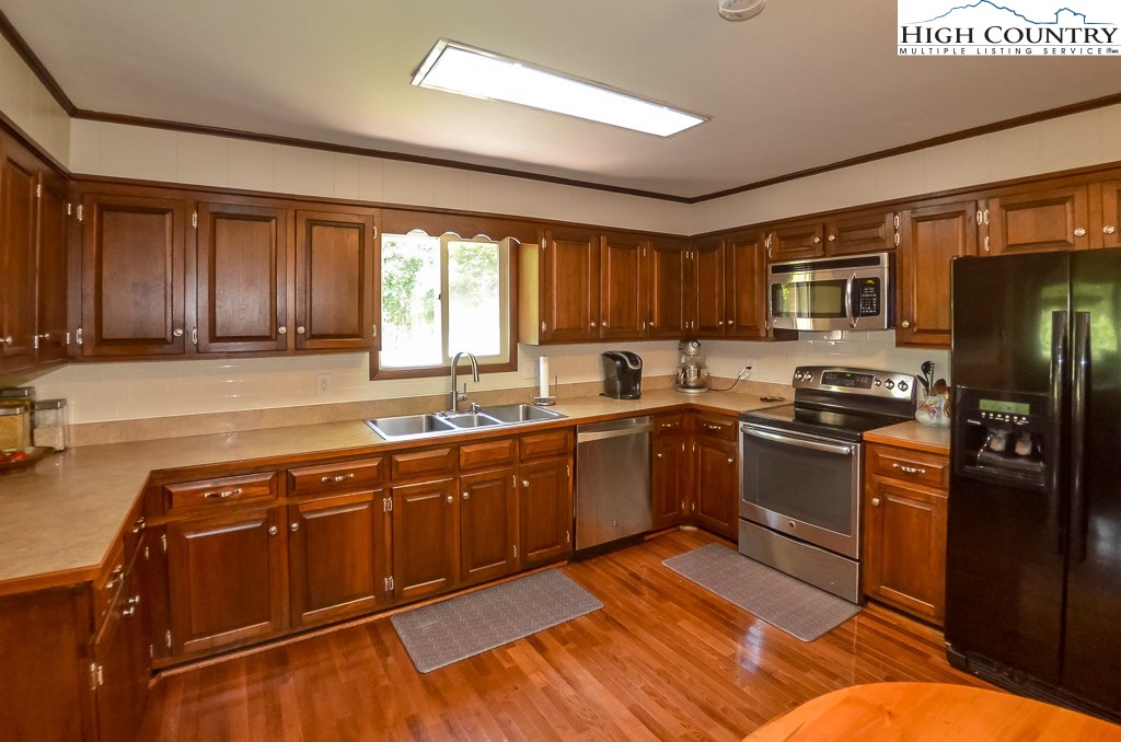 165 Wilson Ridge Road Boone, NC 28607 - Photo 6 of 22 a kitchen with stainless steel appliances granite countertop a stove top oven a sink dishwasher a dining table and chairs with wooden floor