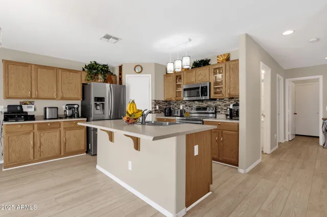 a kitchen with stainless steel appliances granite countertop a stove top oven a sink dishwasher and a refrigerator with wooden floor