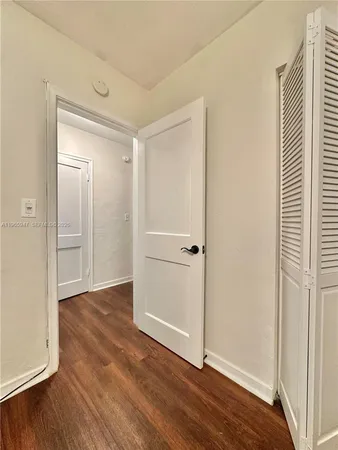 an empty room with wooden floor & closet area