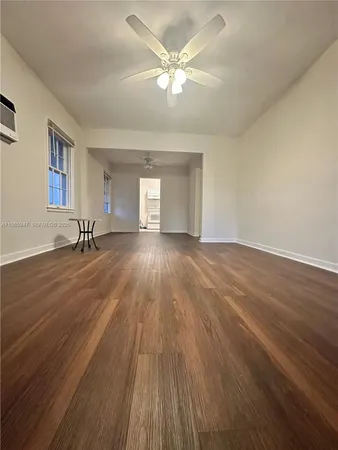 a view of a room with wooden floor and a ceiling fan