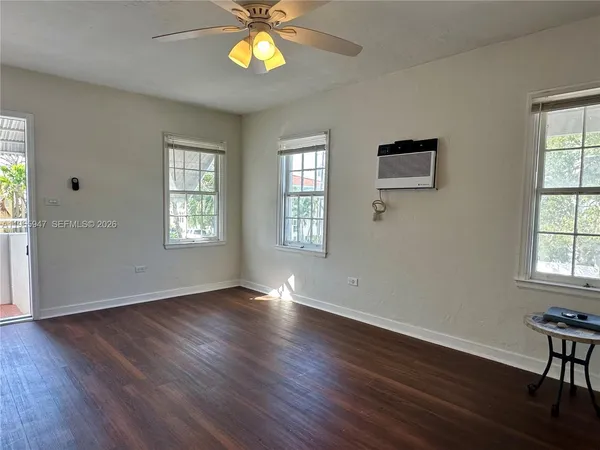 a view of an empty room with a window and wooden floor