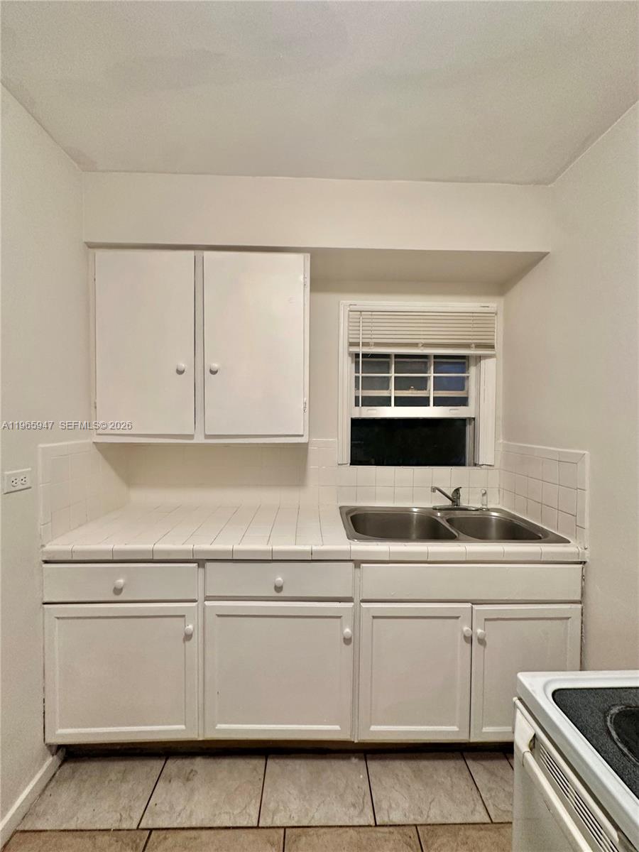 430 76th Street, Unit 4 Miami Beach, FL 33141 - Photo 10 of 24 a kitchen with white cabinets and white appliances
