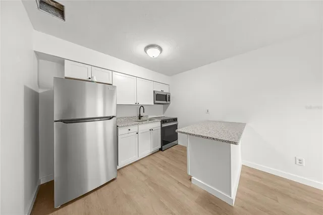 an empty room with wooden floor and ceiling fan