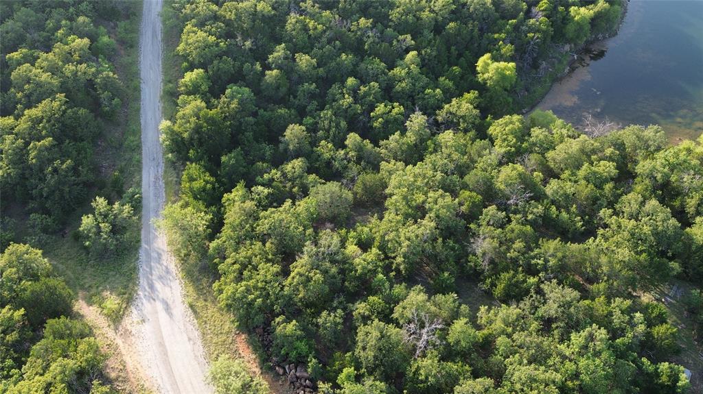 0 Mallard Circle Gordon, TX 76453 - Photo 6 of 12 Aerial perspective showcasing a natural landscape with dense tree coverage, a visible water body, and an unpaved road